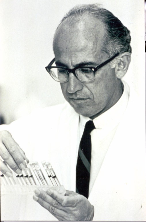 Image of Jonas Salk, the inventor of the Salk vaccine. He is holding a set of syringes. 