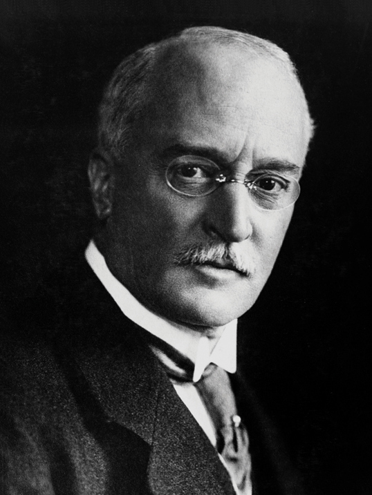 Image of Rudolf Diesel the inventor of the diesel engine. He is shown in  black and white picture wearing glasses and a suit and tie.