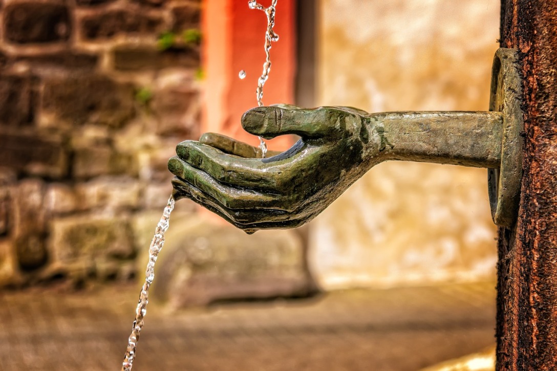 Bronze statue of hands catching water as it falls.